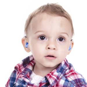 A boy with a hearing aids on gray background